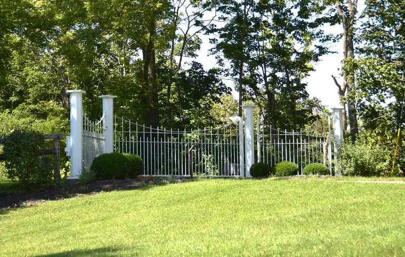 White metal fence with square posts in a green garden
