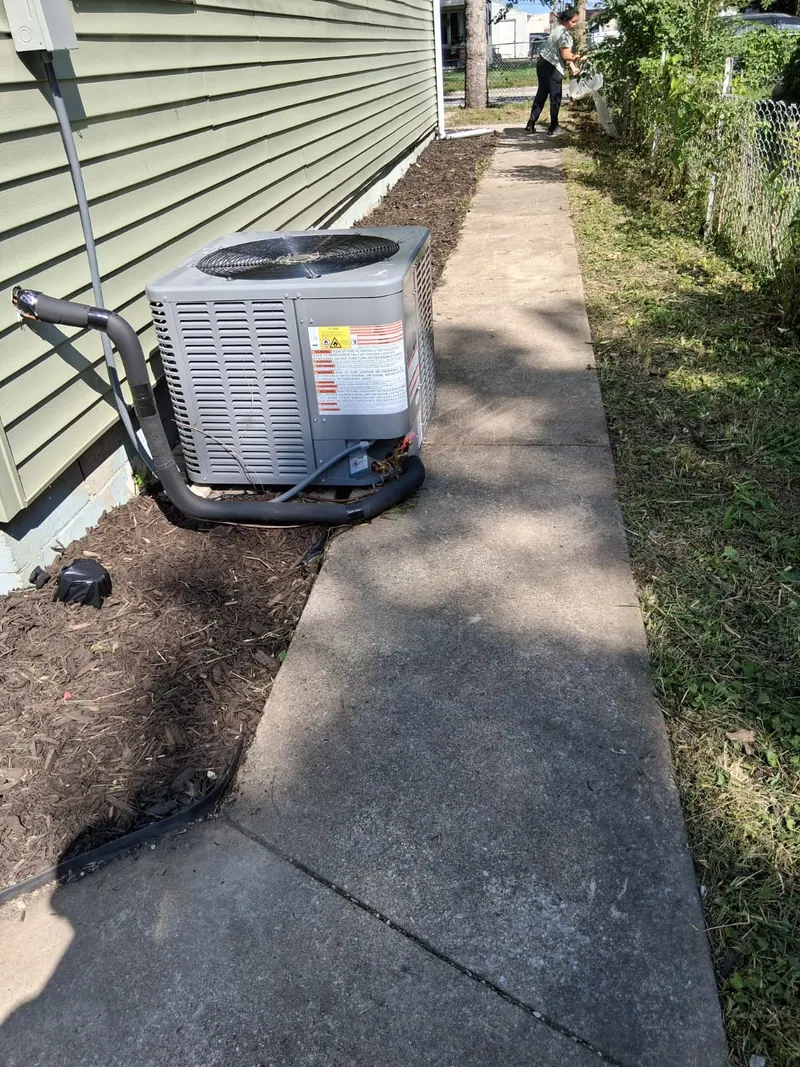 Outdoor air conditioning condenser with insulated refrigerant lines beside the house