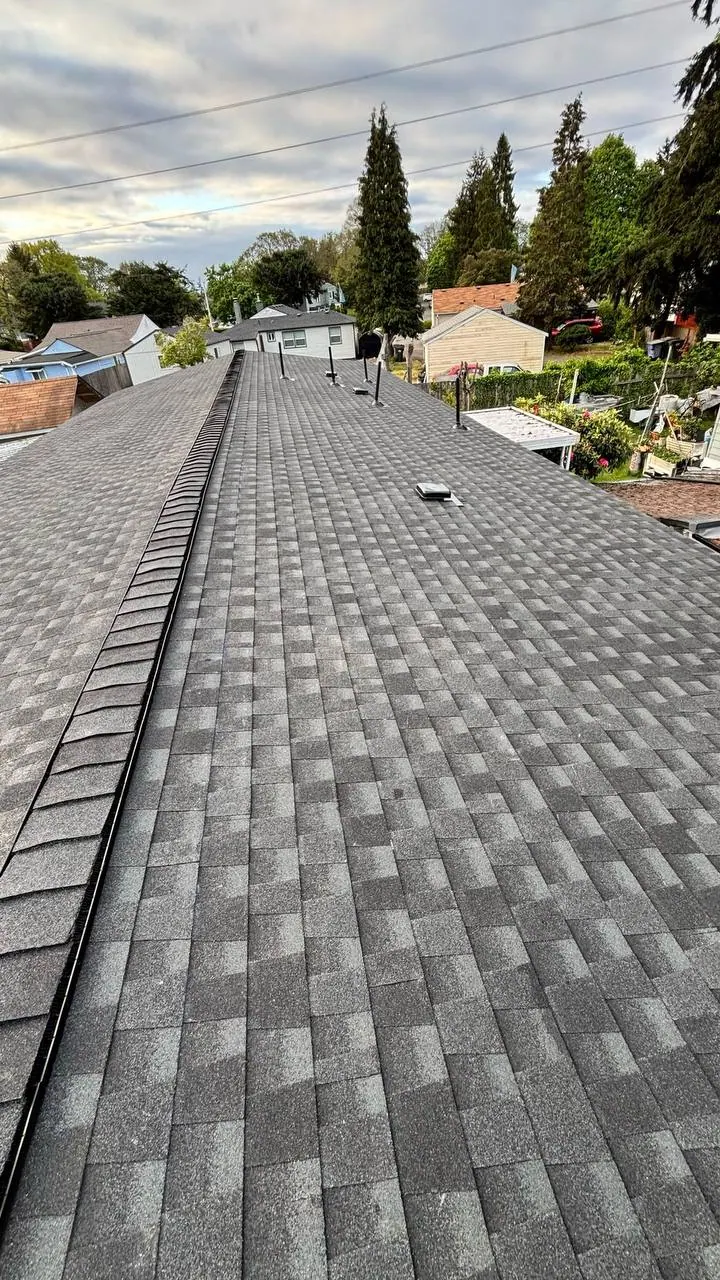 Dark gray asphalt shingle roof with ridge cap and roof vents on a residential home.